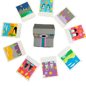 May include: A grey paper camera with pink and teal stripes, surrounded by nine small, square images. The images show scenes like landscapes, shoes, and floral patterns, all in a colourful, cartoon style.