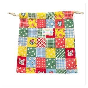 Puede incluir: Una bolsa de cordón de retazos colorida con un patrón amarillo, rojo, verde y azul. La bolsa tiene una pequeña etiqueta que dice "Sunshine" con un gráfico de arcoíris.