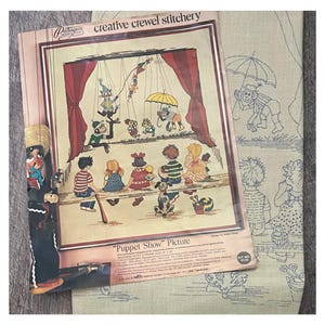 May include: A vintage needlepoint kit featuring a colorful illustration of a puppet show. The kit includes a pre-printed canvas, yarn, and instructions. The kit is titled "Puppet Show" Picture. The kit number is 9122.