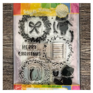 Puede incluir: Juego de sellos transparentes con diseños navideños. Incluye coronas, un lazo, un zorro, un oso, una taza con un corazón y las palabras "MERRY CHRISTMAS". Los sellos están empaquetados en una funda de plástico transparente.