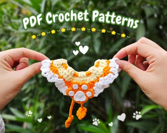 May include: A crocheted pet collar with a white ruffle, orange and yellow stripes, and a white paw print. The collar is being held by two hands against a green background.