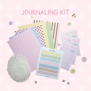Puede incluir: Un kit de journaling con papel estampado, cinta washi y elementos decorativos. El kit incluye papel rosa, amarillo y azul con diseños, además de cinta washi en varios colores pastel. El texto "JOURNALING KIT" se muestra en la parte superior.