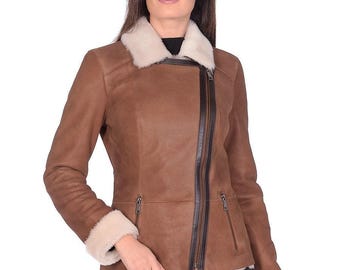 May include: Brown leather jacket with a cream-colored shearling collar and cuffs. The jacket features a diagonal zipper closure, two zippered pockets, and a tailored fit. The jacket is a classic outerwear piece.