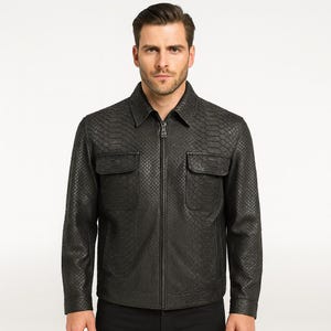 Puede incluir: Chaqueta de cuero negra con un patrón de piel de serpiente. La chaqueta tiene cuello, dos bolsillos en el pecho y una cremallera completa. La chaqueta es de color carbón oscuro.