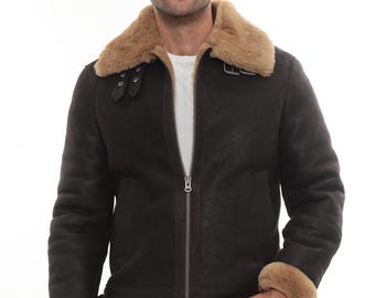 Puede incluir: Chaqueta de borrego marrón oscuro con cuello y puños de borrego color canela. La chaqueta tiene cremallera frontal y cuello abrochado. El modelo lleva una camiseta blanca y pantalones negros.