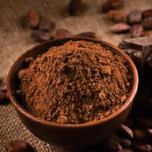 Puede incluir: Primer plano de un cuenco marrón lleno de polvo de cacao marrón oscuro. El cuenco está sobre una superficie de arpillera con granos de cacao esparcidos a su alrededor.
