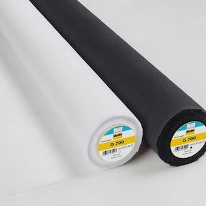 Pode incluir: São mostrados dois rolos de tecido, um branco e um preto. Os rolos são cilíndricos, com as extremidades dos rolos voltadas para o espectador. O rolo branco está à esquerda e o rolo preto à direita. Cada rolo tem um rótulo com texto.