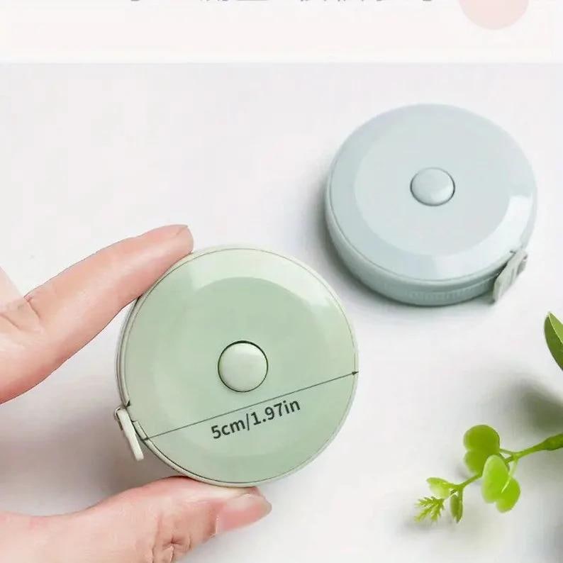 May include: Two round measuring tapes, one light blue and one light green. The green tape has a white button and the text "5cm/1.97in" printed on it.