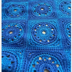 May include: Blue crochet fabric with a repeating pattern of circular designs. The fabric has a textured, hand-stitched look.