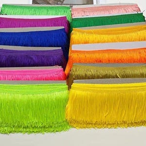 May include: Assortment of colourful fringe trim in various colours, including pink, green, blue, purple, yellow, and orange. The fringe is approximately 2.5 cm wide and is perfect for adding a touch of whimsy to any project.