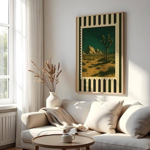 May include: A framed art print featuring a desert landscape with a Joshua tree under a starry night sky. The artwork is designed to resemble a postage stamp, with a green and cream striped border. The print is displayed in a living room setting.