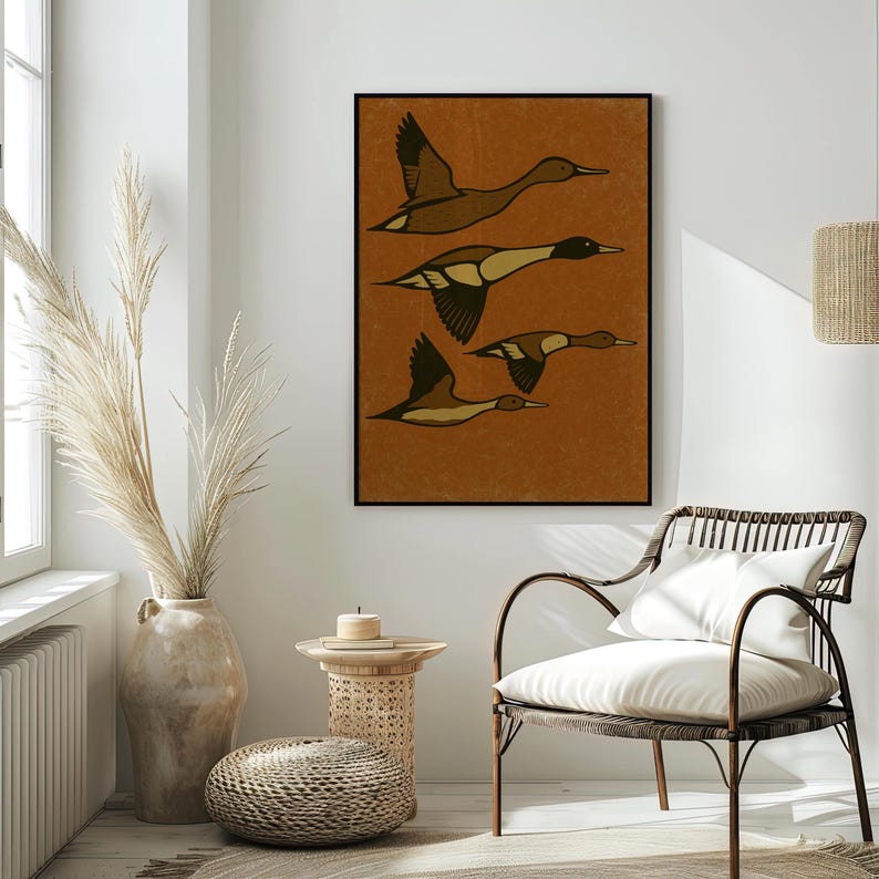Pu&ograve; includere: Una stampa artistica incorniciata con quattro anatre stilizzate in volo. Gli uccelli sono raffigurati in tonalit&agrave; di marrone e nero su uno sfondo strutturato color ruggine. L'opera d'arte &egrave; esposta in una stanza con una palette di colori neutri, tra cui una sedia intrecciata e un vaso decorativo.