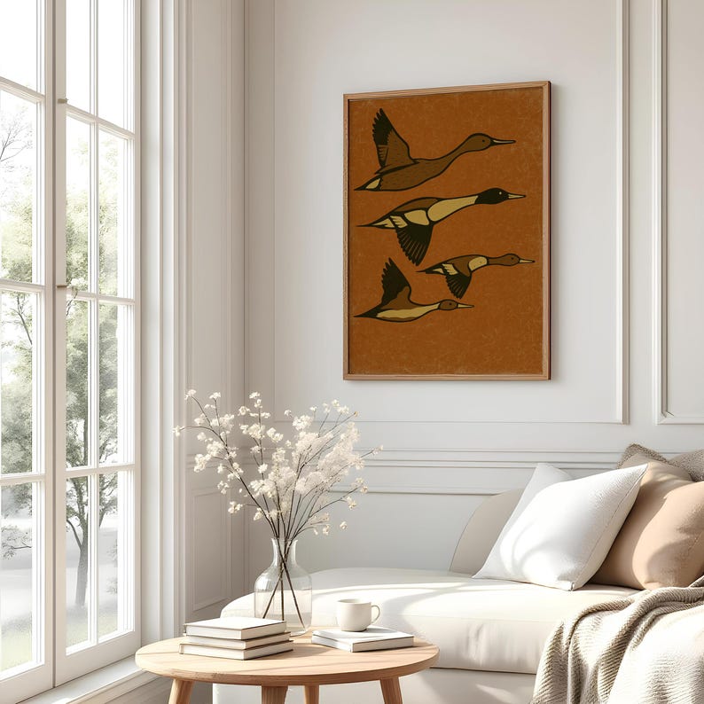 Pu&ograve; includere: Una stampa artistica incorniciata con quattro anatre stilizzate in volo. L'opera d'arte ha una calda tavolozza di colori terrosi con toni marroni e beige. Le anatre sono raffigurate con ali e corpi marrone scuro, su uno sfondo arancione strutturato.