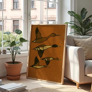 Pu&ograve; includere: Una stampa artistica incorniciata con quattro anatre stilizzate in volo. L'opera d'arte ha una calda tavolozza di colori terrosi con sfumature di marrone e beige. Le anatre sono raffigurate con ali e corpi dettagliati, su uno sfondo strutturato.