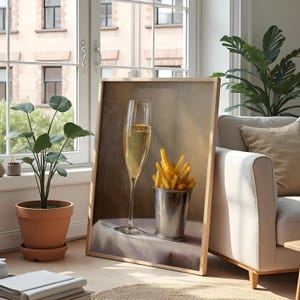 May include: A framed artwork depicts a champagne flute and a metal bucket filled with french fries. The champagne glass is tall and slender, filled with bubbly liquid. The fries are golden brown. The artwork is leaning against a wall near a window.