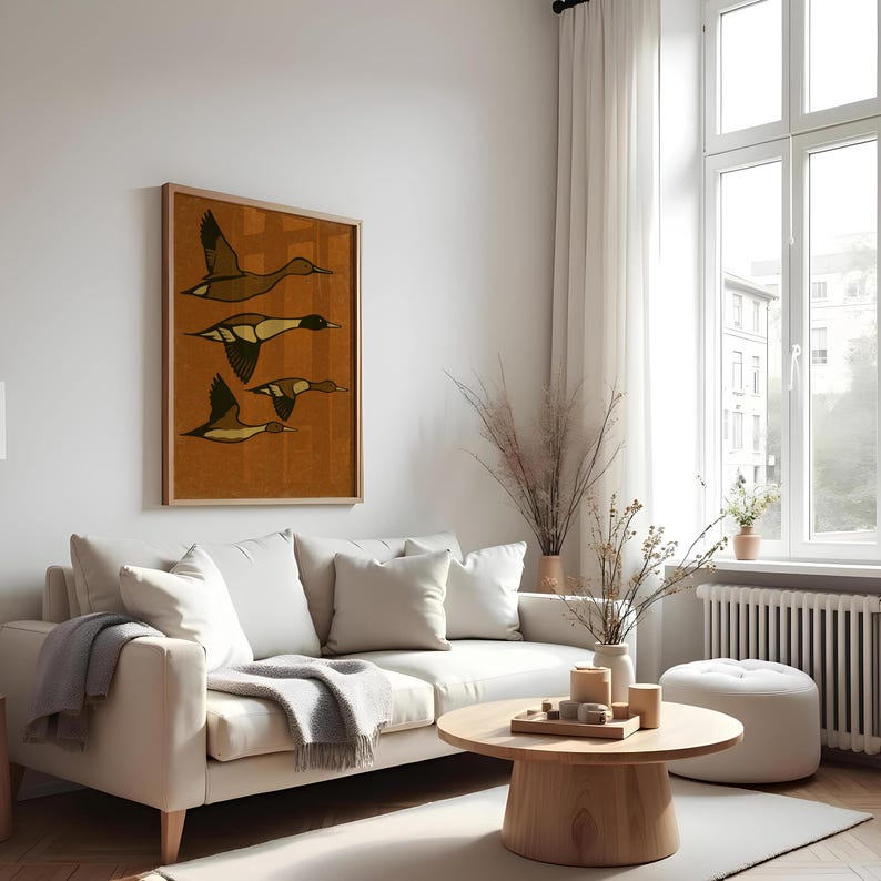 Pu&ograve; includere: Una stampa artistica incorniciata con quattro anatre stilizzate in volo. L'opera d'arte ha uno sfondo caldo marrone-arancio con le anatre raffigurate in tonalit&agrave; marroni e nere. La cornice &egrave; color legno chiaro.