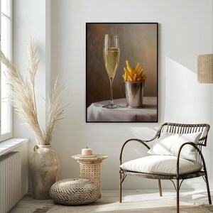 May include: A framed print featuring a champagne flute and a metal bucket filled with french fries. The champagne glass is filled with bubbly liquid. The fries are golden brown. The print is displayed in a room with a neutral color palette.