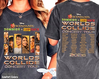 Puede incluir: Una camiseta gris carbón con un gráfico de la gira Disney Descendants, Zombies y Camp Rock Worlds Collide Concert Tour. El frente muestra retratos de personajes y texto de la gira, mientras que la espalda enumera ciudades y 2026.