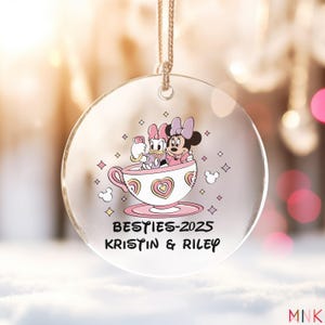 Besties ornament 2025 on a round acrylic ornament showing two best friends in a pastel teacup graphic with personalized names.