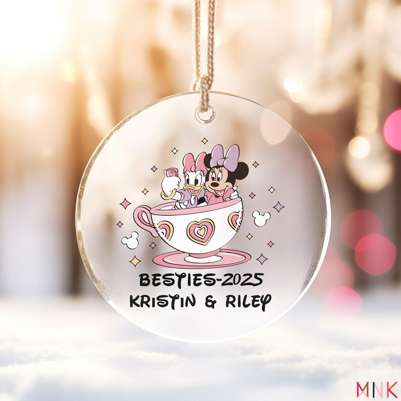 Besties ornament 2025 on a round acrylic ornament showing two best friends in a pastel teacup graphic with personalized names.