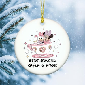 Besties ornament 2025 on a round ceramic ornament featuring two friends in a pink teacup illustration with personalized names.
