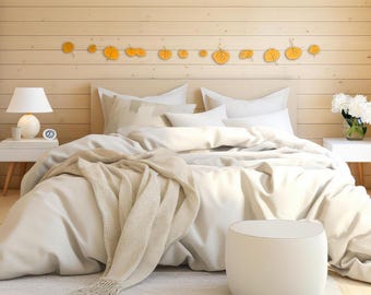 May include: A white bed with white bedding and a white throw blanket. The bed has a white headboard and is decorated with a row of yellow leaf wall decor. A white ottoman sits in front of the bed.