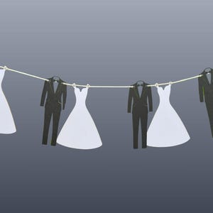 May include: A decorative banner featuring cut-out shapes of black suits and white wedding dresses hanging from a string. The suits have a tuxedo design, and the dresses are in a classic bridal style. The background is a gradient of gray.
