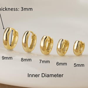 Può includere: Sono presentati cinque orecchini a cerchio dorati di varie dimensioni. Gli orecchini variano da 5 mm a 9 mm di diametro interno, con uno spessore di 3 mm. Il testo "Inner Diameter" è sotto.