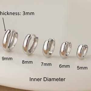 Op de afbeelding: Een set van vijf zilverkleurige oorringen in verschillende maten, variërend van 5 mm tot 9 mm binnendiameter. De oorbellen zijn 3 mm dik. De tekst "Inner Diameter" staat onder de oorbellen.