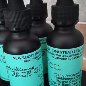 May include: Four 1-fluid ounce bottles of face oil with teal labels. The labels have black text that reads "New Roots Homestead Lee, ME", "newrootshomestead@yahoo.com", "NewRootsShop.etsy.com", "Revitalizing Face Oil", and a list of ingredients.