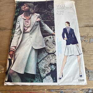 Pode incluir: Padrão de costura vintage Vogue Americana Anne Klein. A capa apresenta uma mulher em um terno de saia cinza claro com uma blusa rosa e um colar de pérolas. Uma segunda ilustração mostra um blazer azul marinho e uma saia branca. O número do padrão é 2825.