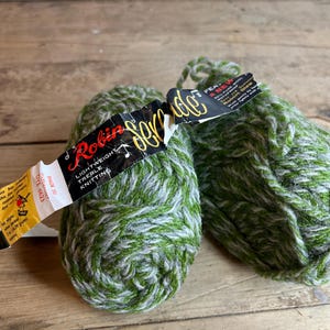 May include: Two balls of green and white yarn with labels that read "Robin Shade 350 Dye 8623" and "FEA NEW SOIL PURE WOOL Robert Glew"