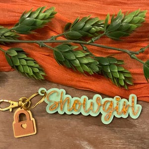Sparkle trendy orange and green showgirl keychain and charm. Trendy perfect for any wardrobe.