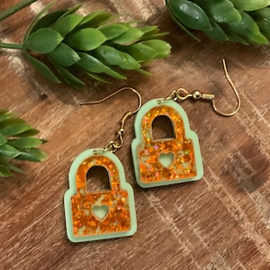 Orange glitter and green showgirl lock earrings. Trendy, pop of sparkle for any wardrobe.