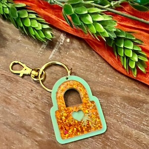 Orange glitter and green showgirl lock keychain.Trendy, pop of sparkle for anyone.