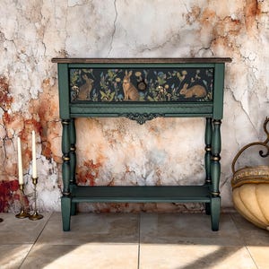 Unique artisan console table in deep green with hand-painted floral and animal artwork on the front panel, ornate carved scroll details, handcrafted decorative furniture for entryway, hallway, or living room.