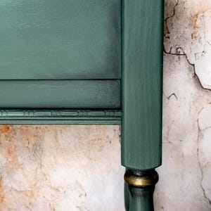 Rear panel close-up of green console table showing ornate carved trim and aged vintage patina, distressed artisan finish for collectible accent furniture.