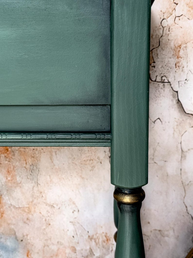 Rear panel close-up of green console table showing ornate carved trim and aged vintage patina, distressed artisan finish for collectible accent furniture.