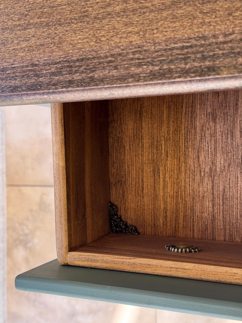 Handcrafted console table drawer interior showing rich natural wood texture finished with oil and detailed corner ornaments in antique brass style, artisan decorative furniture.