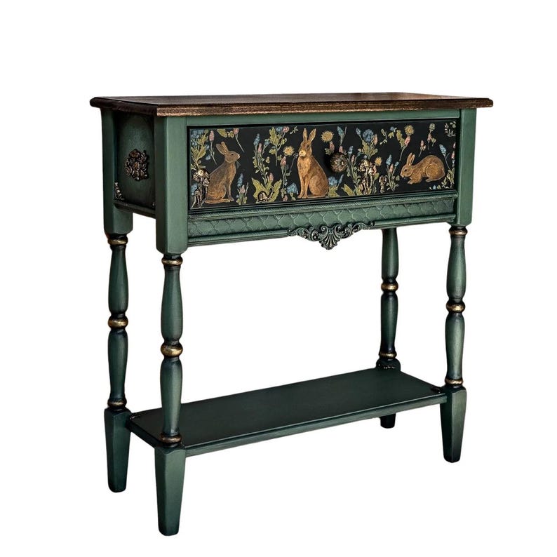 Green hand-painted console table with a woodland rabbit motif, shown isolated on a white background. The table features turned legs, gold accents, a detailed floral front panel, and a lower shelf.