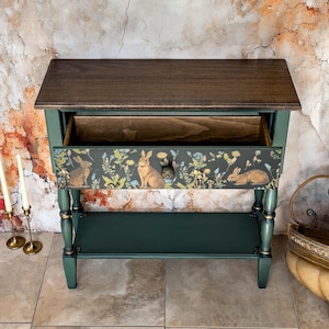 Unique hand-painted green console table with open drawer, decorative floral and animal artwork inside, ornate carved trim, artisan functional art furniture for entryway or living room.