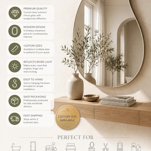 May include: An irregular, organic-shaped wall mirror with a thin gold frame. The mirror is displayed above a light wood floating console table, which holds a ceramic vase with olive branches, a small wooden bowl, and two stacked books.