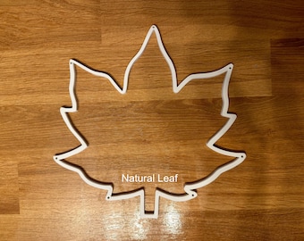 May include: White outline of a maple leaf on a wood background. The text "Natural Leaf" is printed below the leaf.