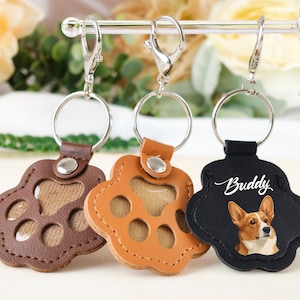 May include: Three paw-shaped keychains in brown, tan, and black leather. The brown and tan keychains have a paw print design. The black keychain features a corgi illustration and the name "Buddy". Each keychain has a silver keyring.