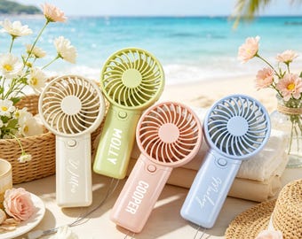 May include: Four handheld portable fans in pastel colors of cream, light green, peach, and light blue. Each fan features a circular head with a protective grille, a handle with a power button, and a wrist strap. The names Willow, Molly, Cooper, and Marley are printed in white on the handles.