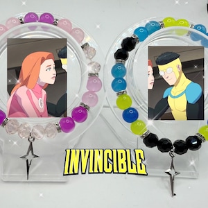 May include: Two beaded bracelets with images of characters from the animated series Invincible. One bracelet features pink and purple beads, the other blue, black, and yellow. Each has a star charm and the word "INVINCIBLE".