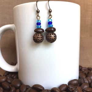 May include: A pair of earrings with brown metal balls and blue and light blue beads hanging from bronze hooks.