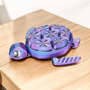 May include: A 3D printed purple and blue iridescent turtle figurine with a detailed shell and large eyes.