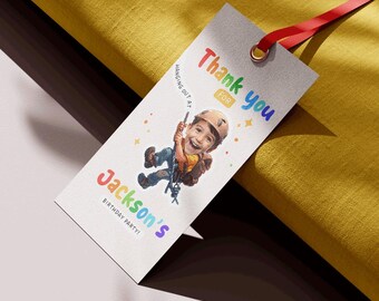 May include: A colorful thank you tag with a cartoon illustration of a child rock climbing. The tag says "Thank you for hanging out at Jackson's Birthday Party!"