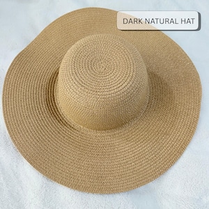 May include: A dark natural hat with a wide brim. The hat is made of woven material in a natural tan color. The crown is rounded and the brim is wide, providing ample shade. The text "DARK NATURAL HAT" is displayed on the top right.